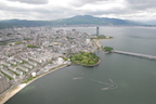 The capital of Shiga Prefecture, the city of Otsu, located at the southern end of Lake Biwa. About 1.4 million people live in Shiga. The anchor-shaped structures in the lake are 'eri' fishing traps. The small, rounded peninsula covered with trees is the old site of Zeze Castle (1601-1870). (12 May 2010)